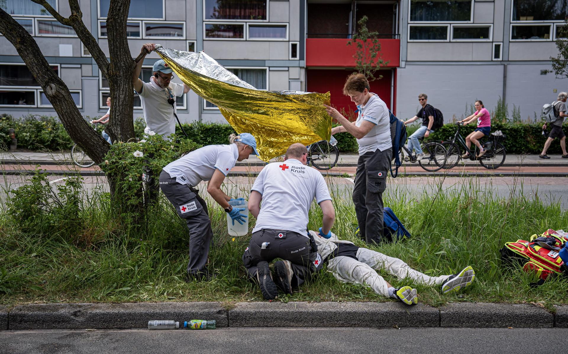 Medewerkers van het Rode Kruis ontfermen zich over een deelnemer die in het zicht van de finish door hitte is bevangen en niet meer verder kan.