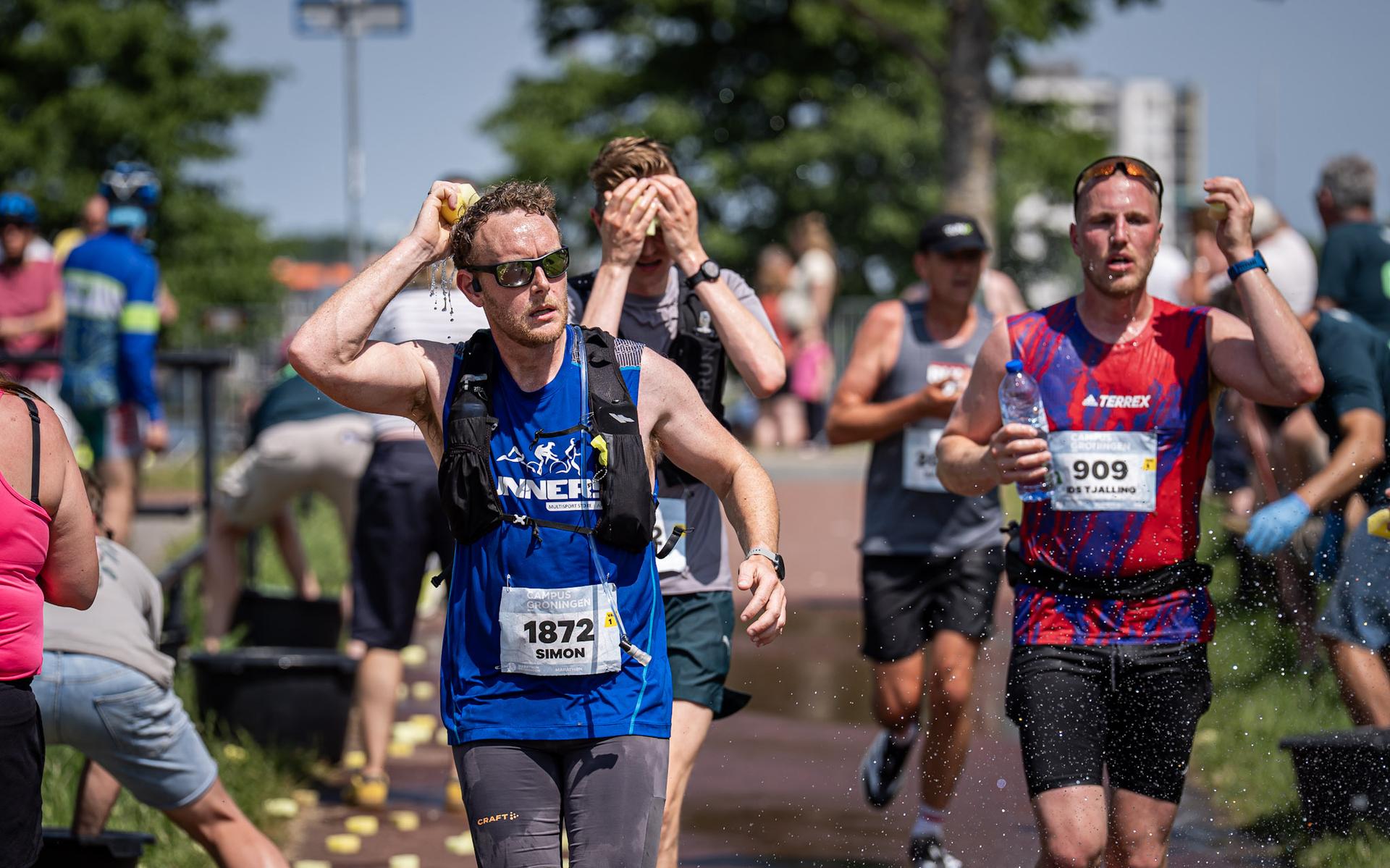 Deelnemers aan de Marathon van Groningen zoeken verkoeling met een natte spons.